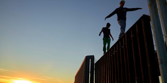 Two Central American migrants walk along the top of the border structure separating Mexico and the United States Wednesday, Nov. 14, 2018, in Tijuana, Mexico. Migrants in a caravan of Central Americans scrambled to reach the U.S. border, catching rides on buses and trucks for hundreds of miles in the last leg of their journey Wednesday as the first sizable groups began arriving in the border city of Tijuana. (AP Photo/Gregory Bull)