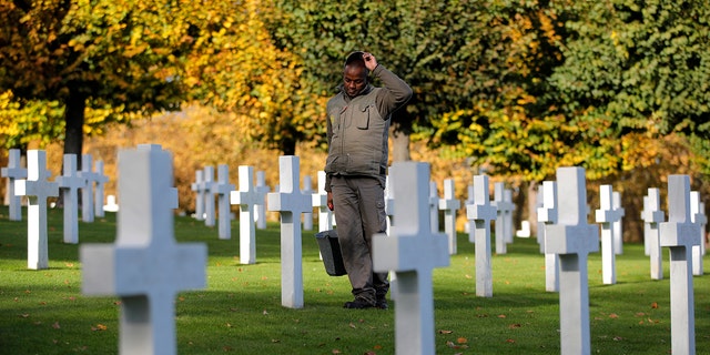 A cemetery employee walks between graves of American service members killed during  World War I at the American Cemetery in Suresnes, on the outskirts of Paris, Nov. 9, 2018.  (Associated Press)