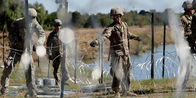 FILE - In this Nov. 16, 2018, photo, members of the U.S. military install multiple tiers of concertina wire along the banks of the Rio Grande near the Juarez-Lincoln Bridge at the U.S.-Mexico border in Laredo, Texas.