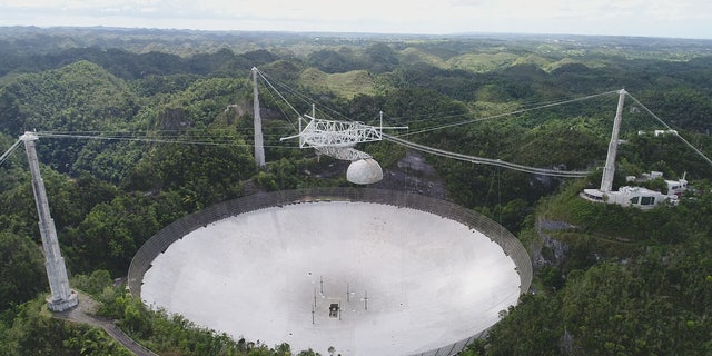 In this recent view of the Arecibo Observatory in Puerto Rico, the 96-foot line-feed antenna that once dangled above the telescope dish is still missing. It broke off during Hurricane Maria and punctured the dish below.
