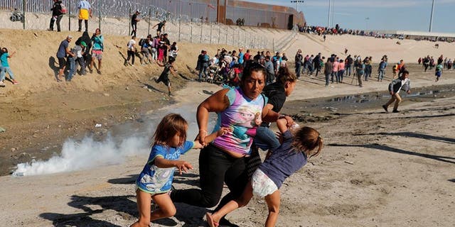 A family of migrants, part of a caravan of thousands of people from Central America heading for the United States, fleeing tear gas at the border wall between the United States and Mexico in Tijuana Sunday.