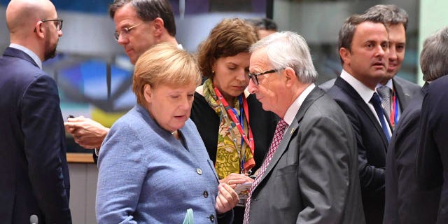 German Chancellor Angela Merkel, left, speaks with European Commission President Jean-Claude Juncker during a round table meeting at an EU summit in Brussels, Sunday, Nov. 25, 2018.
