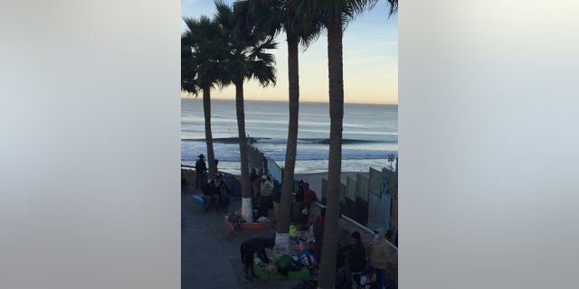 About two dozen migrants who arrived in Tijuana are camped out next to the border fence near the ocean. Others have crammed into already overcrowded shelters or are sleeping in tents.