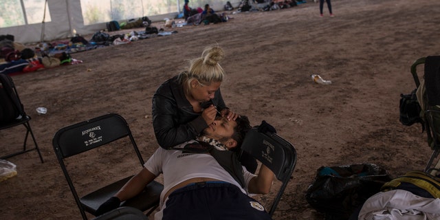 Central American migrant Jenifer Argueta plucks the eyebrows of Honduran Kevin Banegas, while waiting to receive donated food in Palmillas, Mexico, Saturday, Nov. 10, 2018.