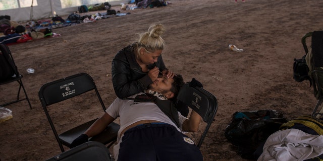 Central American migrant Jenifer Argueta plucks the eyebrows of Honduran Kevin Banegas, while waiting to receive donated food in Palmillas, Mexico, Saturday, Nov. 10, 2018.