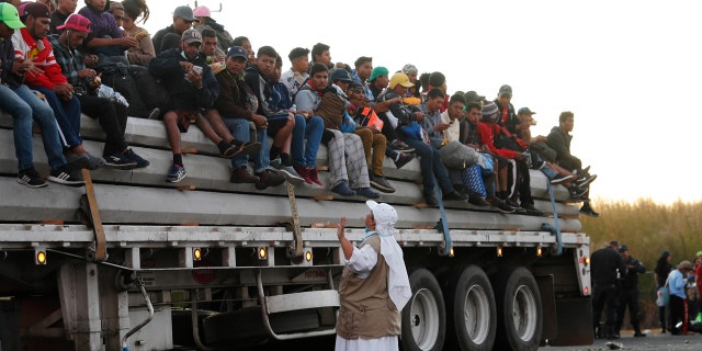 A Catholic nun gives travel advice to Central American migrants riding in the bed of a semi-trailer, as they move toward the U.S. border.