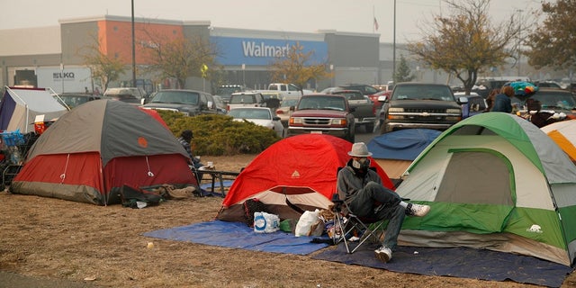 People sit by their tents at a makeshift encampment outside a Walmart store for people displaced by the Camp Fire.