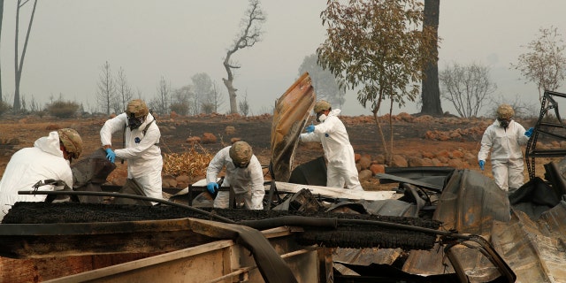 Members of the California Army National Guard search a property for human remains at a home burned in the Camp fire, Wednesday, Nov. 14, 2018, in Paradise, Calif.