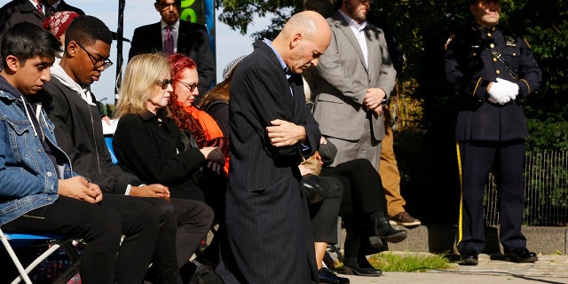 Hugh Hales-Tooke, a friend of victim Nicholas Cleves, kneels during a moment of silence during a ceremony marking the anniversary of the Hudson River Park bike path attack.