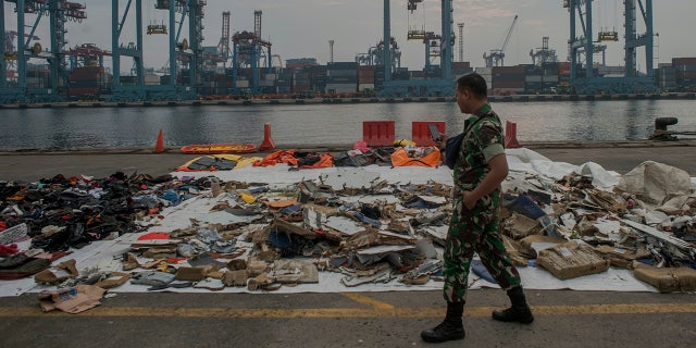 An Indonesian soldiers walk past debris retrieved from the waters where Lion Air flight JT 610 is believed to have crashed at Tanjung Priok Port in Jakarta, Indonesia, Wednesday, Oct. 31, 2018.