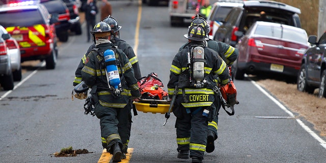 Firefighters carry a stretcher to the scene of a fatal fire at 15 Willow Brook Rd. Tuesday, Nov. 20, 2018, in Colts Neck,N.J.