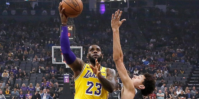 Los Angeles Lakers forward LeBron James, center, drives to the basket between Sacramento Kings' Harry Giles III, left, and Justin Jackson during the second half of an NBA basketball game Saturday, Nov. 10, 2018, in Sacramento, Calif.