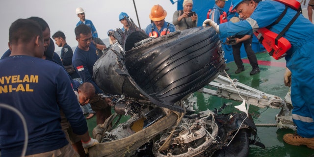 Rescuers inspect part of the landing gears of the crashed Lion Air jet they retrieved from the sea floor in the waters of Tanjung Karawang, Indonesia, Sunday, Nov. 4, 2018.
