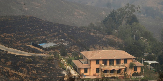 A home is spared after a wildfire swept through Saturday, Nov. 10, 2018, in Malibu, Calif.