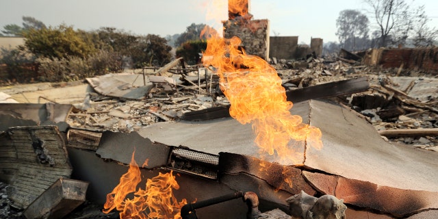 Flames from a broken gas line burn at one of at least 20 homes destroyed just on Windermere Drive in the Point Dume area of Malibu, Calif.