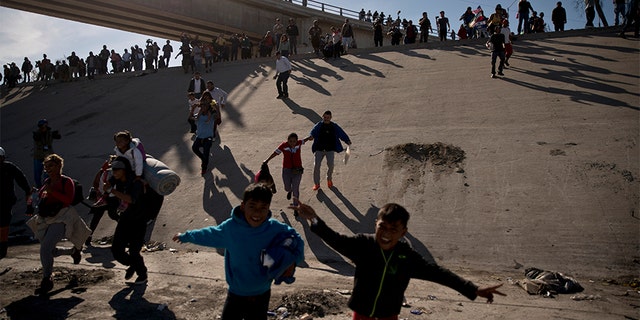 Migrants cross the river at the Mexico-U.S. border after pushing past a line of Mexican police at the Chaparral crossing in Tijuana, Mexico, on Sunday.