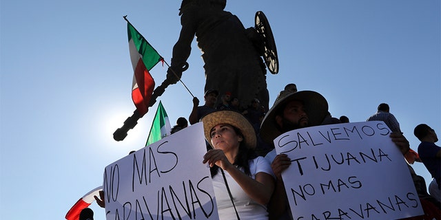 Demonstrators with signs that read in Spanish: "No more Caravans", and "Let's save Tijuana, no more caravans," stand under a statue of indigenous Aztec ruler Cuauhtemoc to protest the presence of thousands of Central American migrants in Tijuana, Mexico, on Sunday.