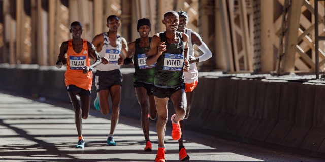 Tola Shura Kitata, of Ethiopia, front, runs with the men's pack as they cross the Queensboro bridge during the New York City Marathon in New York, Sunday, Nov. 4, 2018.