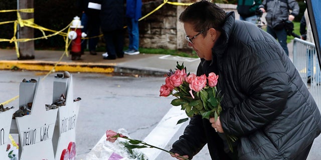 Colleen Cooper lays a single rose on each of the memorials for the eleven people fatally shot last week at the Tree of Life Synagogue after a service, on Saturday in Pittsburgh. (AP Photo/Keith Srakocic)