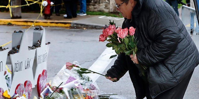 Colleen Cooper lays a single rose on each of the memorials for the eleven people fatally shot last week at the Tree of Life Synagogue after a service, on Saturday in Pittsburgh. (AP Photo/Keith Srakocic)