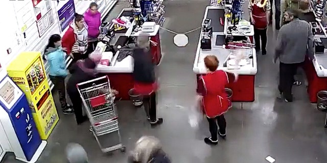 The mother, pictured left at the checkout counter in a red coat, told her cashier that she couldn't wait any longer and that her baby was coming any minute. 