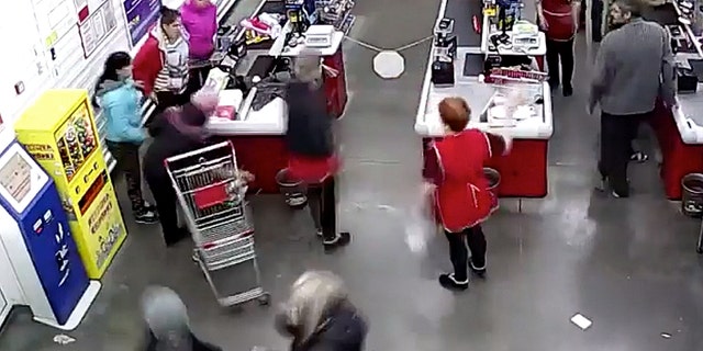 The mother, pictured left at the checkout counter in a red coat, told her cashier that she couldn't wait any longer and that her baby was coming any minute.