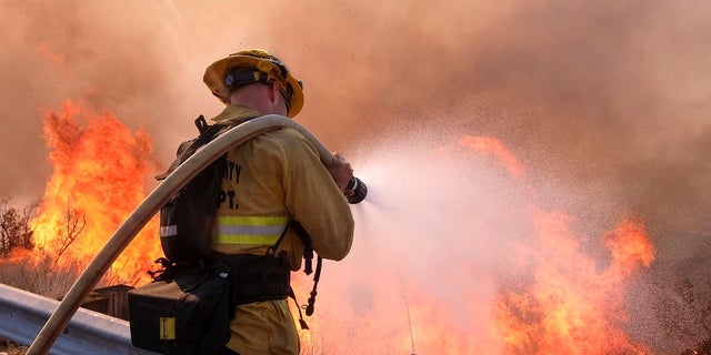 A firefighter battles a blaze along the Ronald Reagan Freeway in Simi Valley, Calif., on Monday, Nov. 12, 2018.