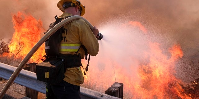 A firefighter battles a blaze along the Ronald Reagan Freeway in Simi Valley, Calif., on Monday, Nov. 12, 2018.