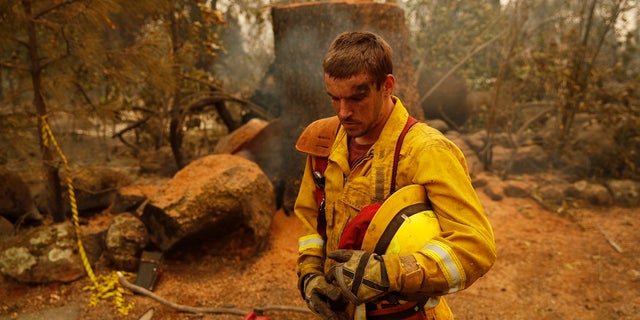 Shawn Slack rests after felling trees burned in the Camp Fire, Monday, Nov. 12, 2018, in Paradise, Calif.