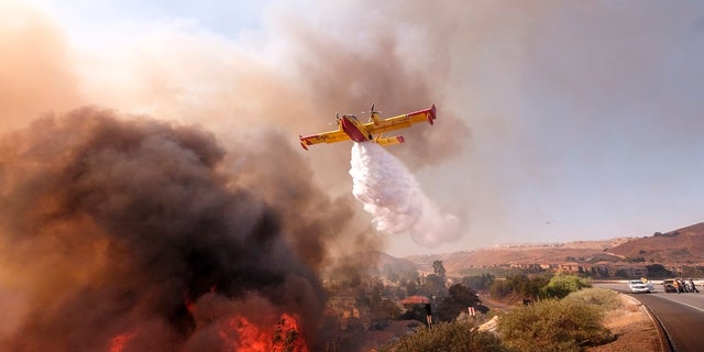 An air tanker seen here dropping water on a fire along the Ronald Reagan Freeway in Simi Valley, Calif., on Monday, Nov. 12, 2018.