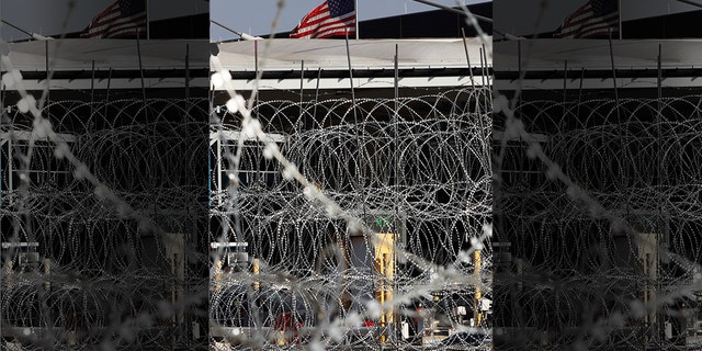 Newly placed barbed wires hangs at the U.S. border fence, where a U.S. flag flies in San Ysidro, seen from Tijuana, Mexico, Monday. The United States closed off northbound traffic for several hours at the busiest border crossing with Mexico to install new security barriers on Monday, a day after hundreds of Tijuana residents protested against the presence of thousands of Central American migrants. (AP Photo/Marco Ugarte)