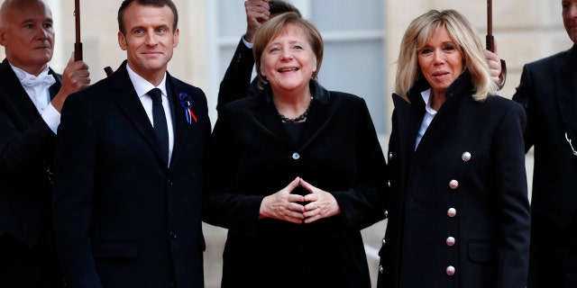 French President Emmanuel Macron and his wife Brigitte, right, welcome German Chancellor Angela Merkel in the courtyard of the Elysee Palace Sunday, Nov. 11, 2018 in Paris.