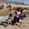 A migrant family, part of a caravan of thousands traveling from Central America en route to the United States, run away from tear gas in front of the border wall between the U.S. and Mexico in Tijuana, Mexico, November 25, 2018. 