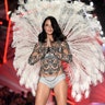 Adriana Lima poses on the runway in an ornate, sequin sheer blouse, topped over a silver bra and underwear set accessorized with feathers. 