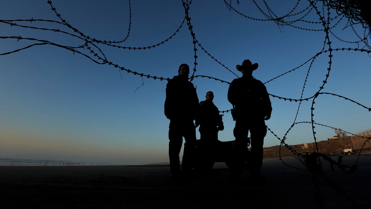 Border patrol officers stand at the beach on the U.S. side of the fence between San Diego and Tijuana, Mexico, Monday, Dec. 24, 2018. Discouraged by the long wait to apply for asylum through official ports of entry, many Central American migrants from recent caravans are choosing to cross the U.S. border wall and hand themselves in to border patrol agents. (AP Photo/Daniel Ochoa de Olza)