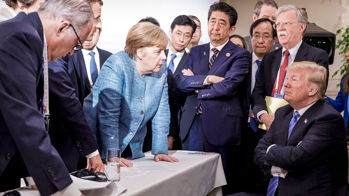 In this photo made available by the German Federal Government, German Chancellor Angela Merkel, center, speaks with U.S. President Donald Trump, seated at right, during the G7 Leaders Summit in La Malbaie, Quebec, Canada, on Saturday, June 9, 2018. (Jesco Denzel/German Federal Government via AP)