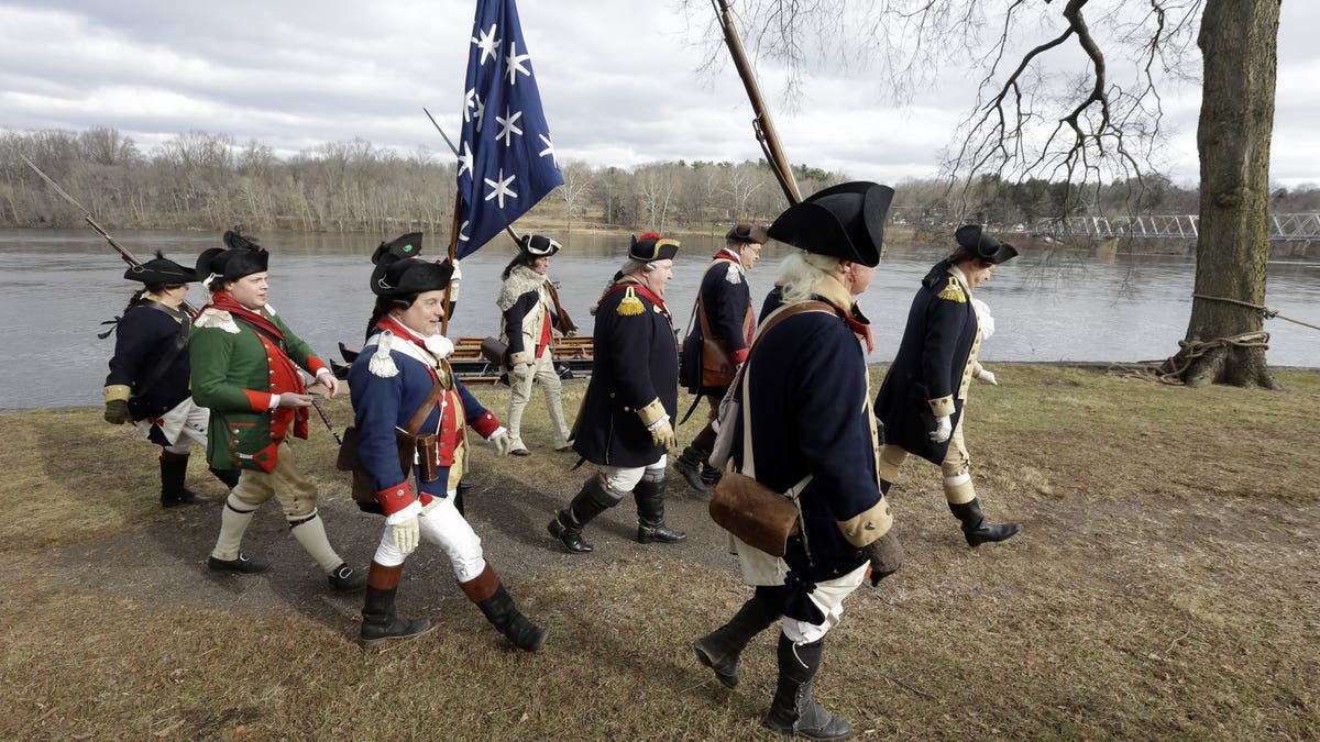 Re-enactor John Godzieba, right, portrays Gen. George Washington as he leads others along the banks of the Delaware River, Tuesday Dec. 25, 2018 in Washington Crossing, Pa.