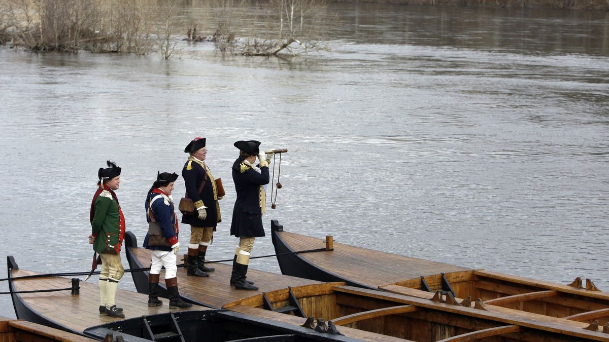 Re-enactor John Godzieba, right, portrays Gen. George Washington as he peers across the Delaware River, Tuesday Dec. 25, 2018 in Washington Crossing, Pa. The annual reenactment of George Washington's daring 1776 crossing of the Delaware River on Christmas Day has once again been left high and dry as organizers announced Monday that the river crossing portion of the reenactment will not take place due to high river conditions following recent rainfall. Other activities carried on as scheduled.