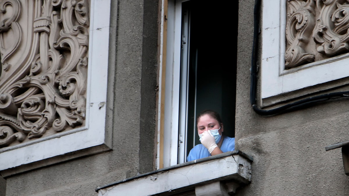 In this Aug. 16, 2010 file photo a nurse looks on from a window of the Giulesti hospital following a fire that left 5 newborn babies dead.