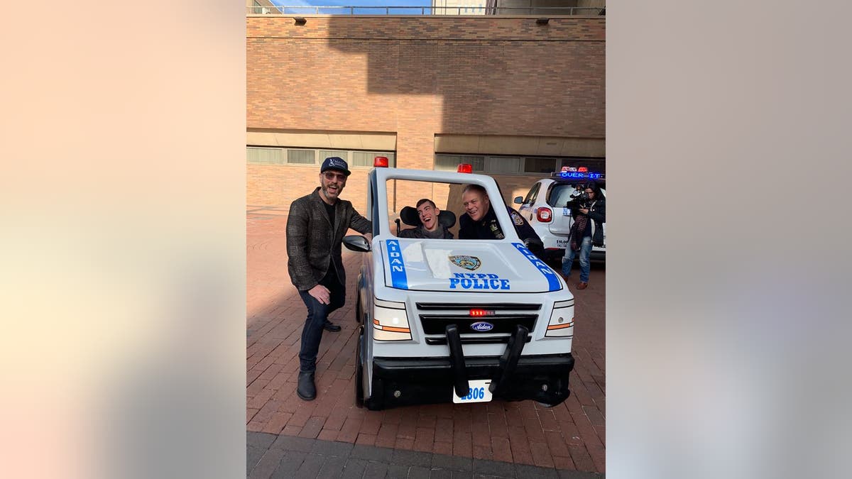 Aidan Riley, pictured with his police officer father and David Vogel, regional director of Magic Wheelchair, received his customized car on Wednesday.