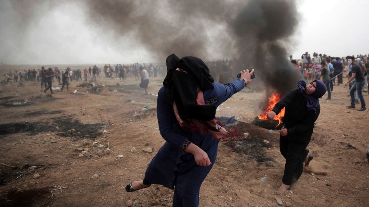 Palestinian women hurl stones at Israeli troops during a protest at the Gaza Strip's border with Israel on May 4, 2018. (AP Photo/ Khalil Hamra)