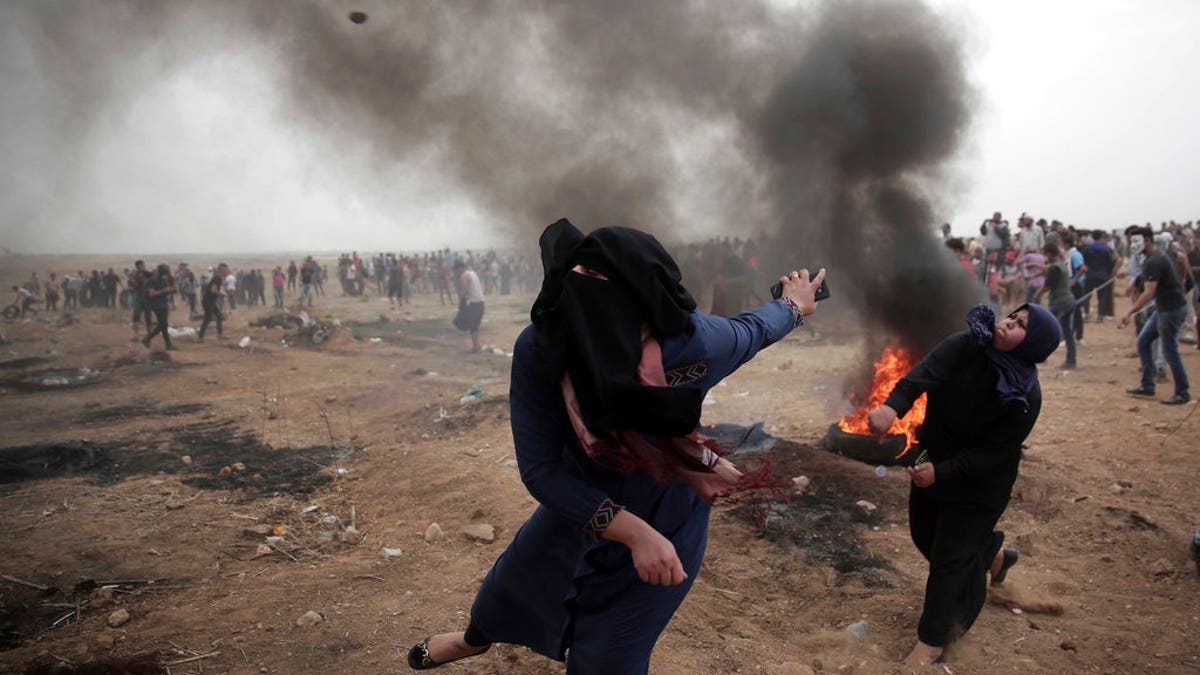 Palestinian women hurl stones at Israeli troops during a protest at the Gaza Strip's border with Israel on May 4, 2018. (AP Photo/ Khalil Hamra)