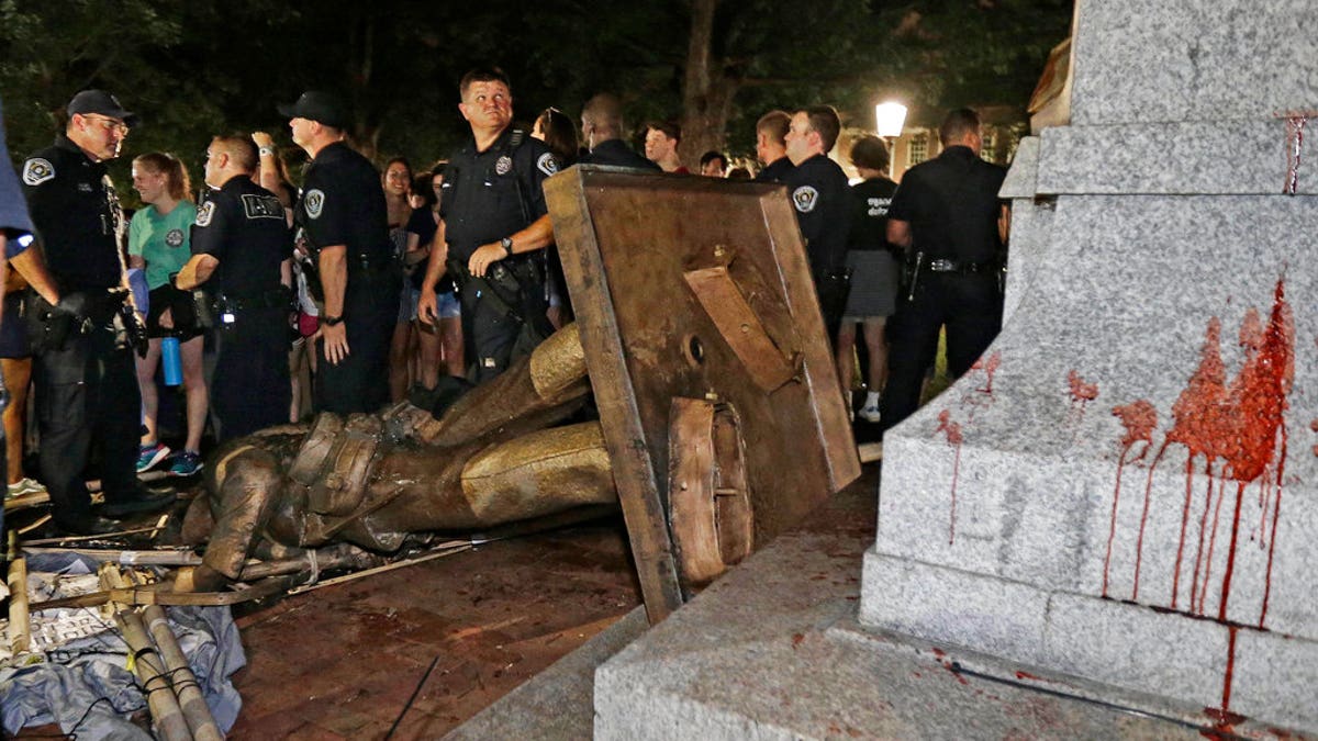 In this Aug. 20, 2018 file photo, police stand guard after the Confederate statue known as Silent Sam was toppled by protesters on campus at the University of North Carolina in Chapel Hill, N.C. A plan to move "Silent Sam" presented by the school on Monday sparked protests hours after campus trustees overwhelming approved the proposal.<br data-cke-eol="1">