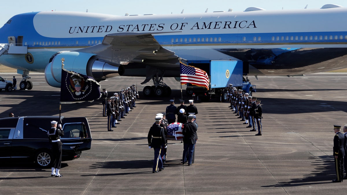 The flag-draped casket of former President George H.W. Bush, is carried by a joint services military honor guard to Special Air Mission 41 at Ellington Field during a departure ceremony Monday in Houston. (AP Photo/Eric Gay)