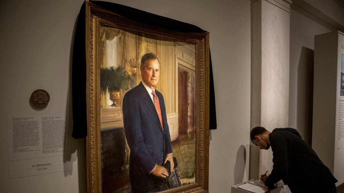 The official portrait of former President George H.W. Bush is draped in black cloth at the National Portrait Gallery before he will lie in state at the Capitol building this week.