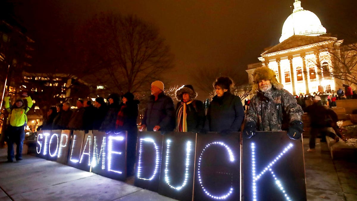 Opponents of an extraordinary session bill submitted by Wisconsin Republican legislators hold "Stop Lame Duck" signs at a rally outside the Wisconsin state Capitol in Madison, Wis., Monday, Dec. 3, 2018. (John Hart/Wisconsin State Journal via AP)