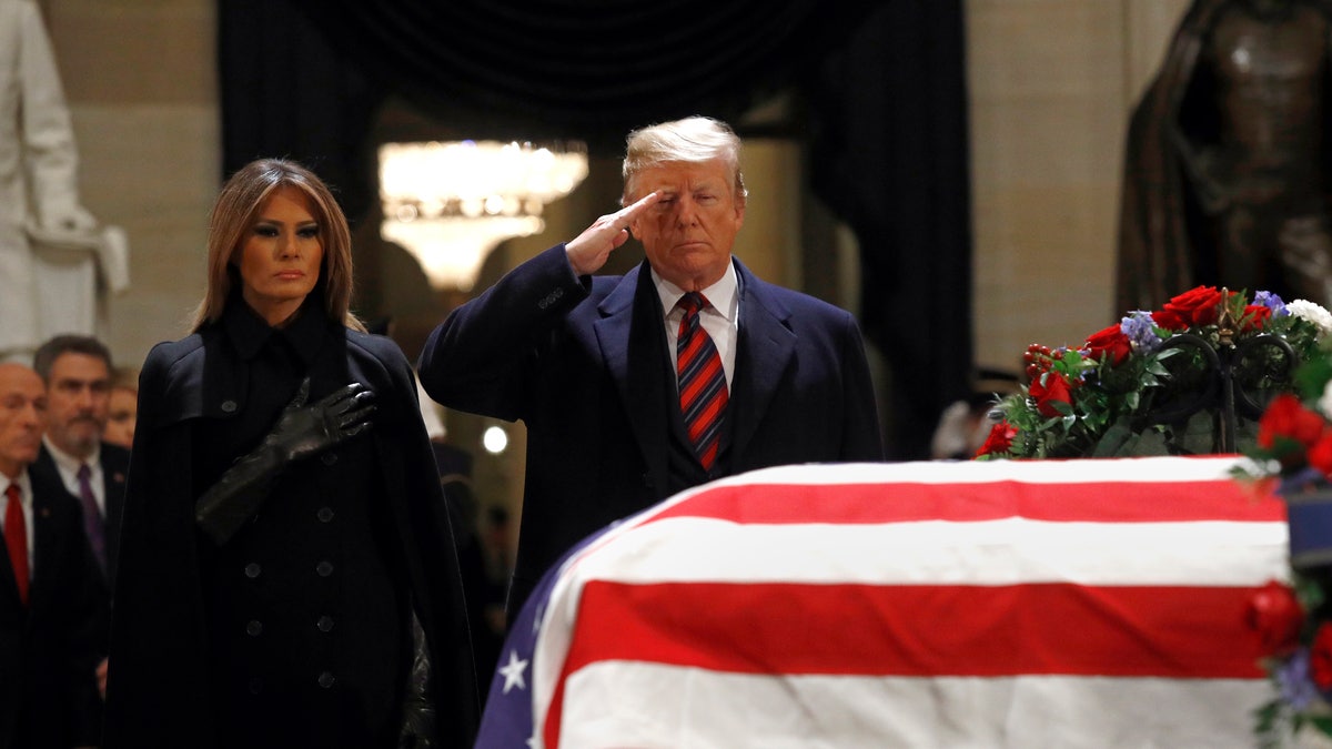 President Donald Trump salutes alongside first lady Melania Trump in front of the flag-draped casket of former President George H.W. Bush in the Capitol Rotunda.