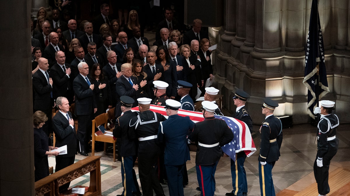 The flag-draped casket of former President George H.W. Bush is carried by a military honor guard past former President George W. Bush and his wife Laura Bush, President Donald Trump, first lady Melania Trump, former President Barack Obama, Michelle Obama, former President Bill Clinton, former Secretary of State Hillary Clinton, former President Jimmy Carter, and Rosalynn Carter at the conclusion of a State Funeral at the National Cathedral.