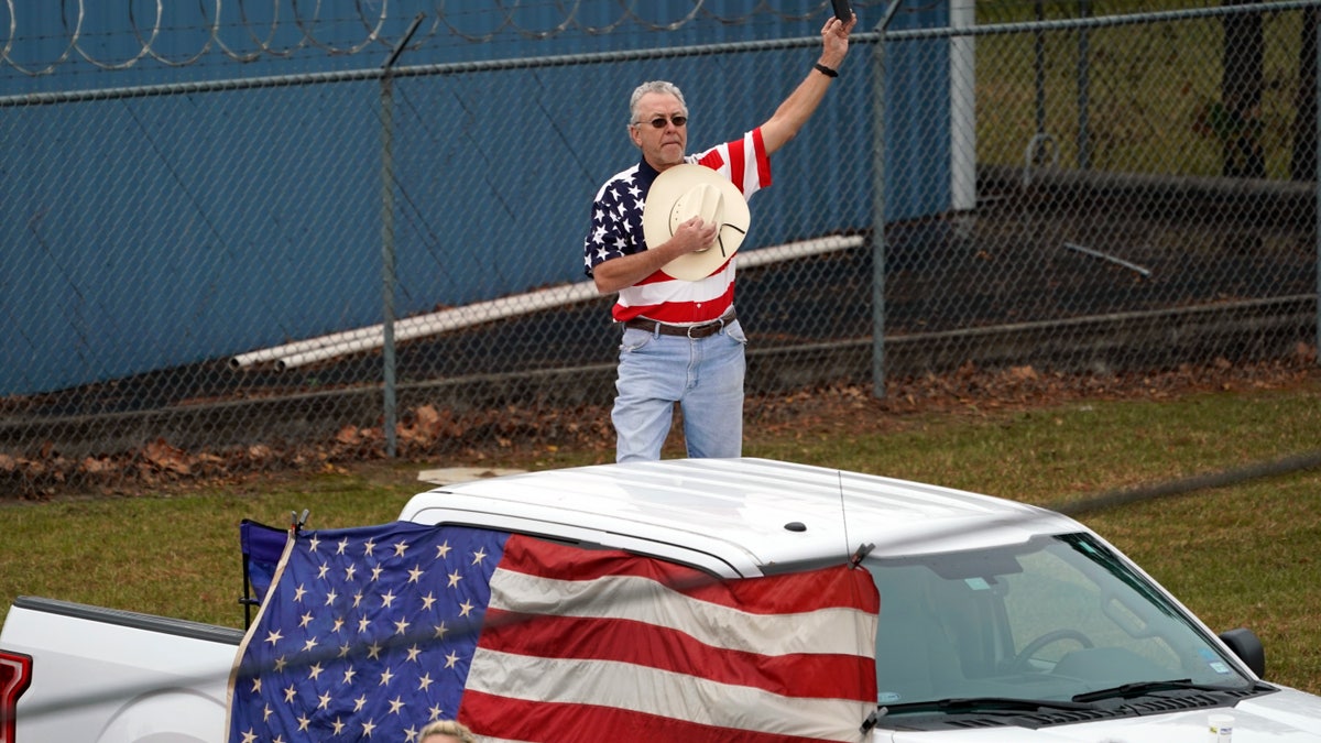 A man makes a patriotic display as the train carrying the casket of former President George H.W. Bush passes.