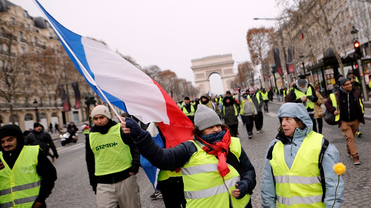 Demonstrators wearing yellow vests walk down the Champs-Elysees avenue, Saturday, Dec. 15, 2018 in Paris. A strong police presence has deployed in Paris before planned demonstrations by the "yellow vest" protesters, with authorities repeating calls for calm after previous violent protests and rioting.